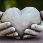 conceptual sculpture with hands holding a heart